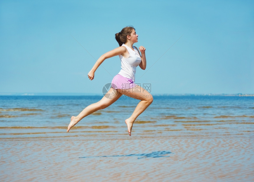 运动天空微笑迷人的年轻女子独自在海滩上奔跑图片