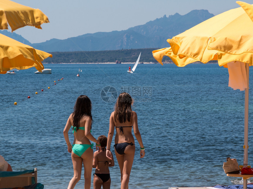 水采取旅行黄色海滩伞状后视线附近比基尼的两名年轻女孩图片
