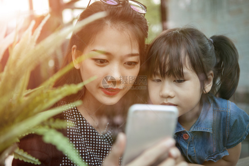 正在家中客厅寻找智能电话屏幕的年青亚洲小妇幼女和儿童互联网消息技术图片