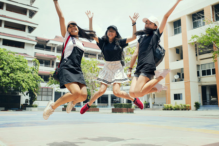 漂浮活动三名亚洲青少年在中空跳跃与学校建筑背景的快乐情绪相抗争女士图片