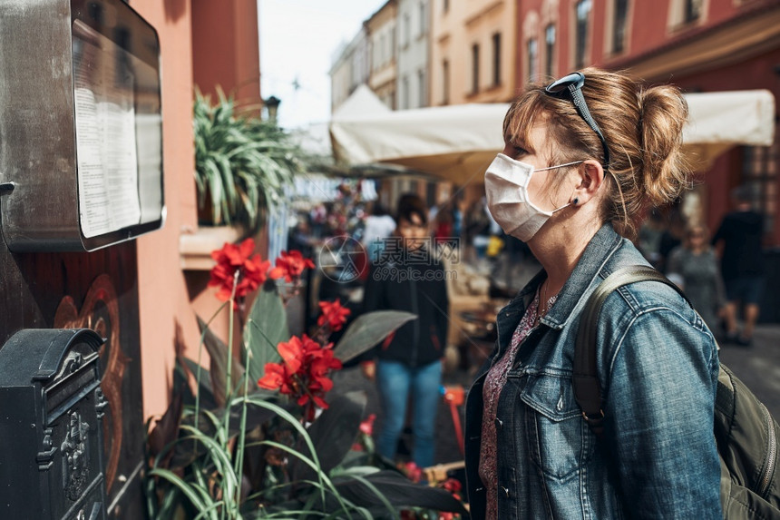 人群站在市区街头的年轻女子站立在街上望着身戴面罩的一边以避免感染防止疾病在出现冠状腺毒时蔓延大流行保护的图片