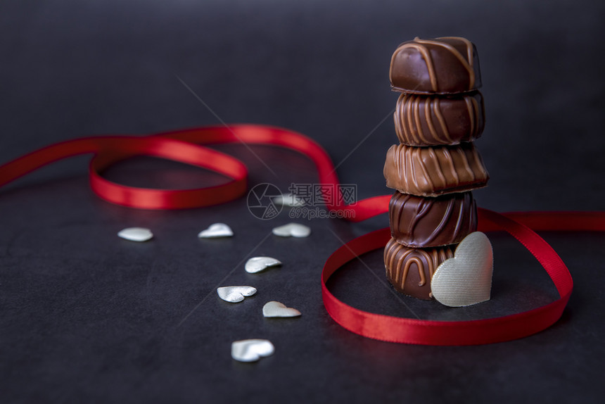巧克力糖果堆叠和黑色背景的红丝带巧克力专注于黑色的可口欲望图片