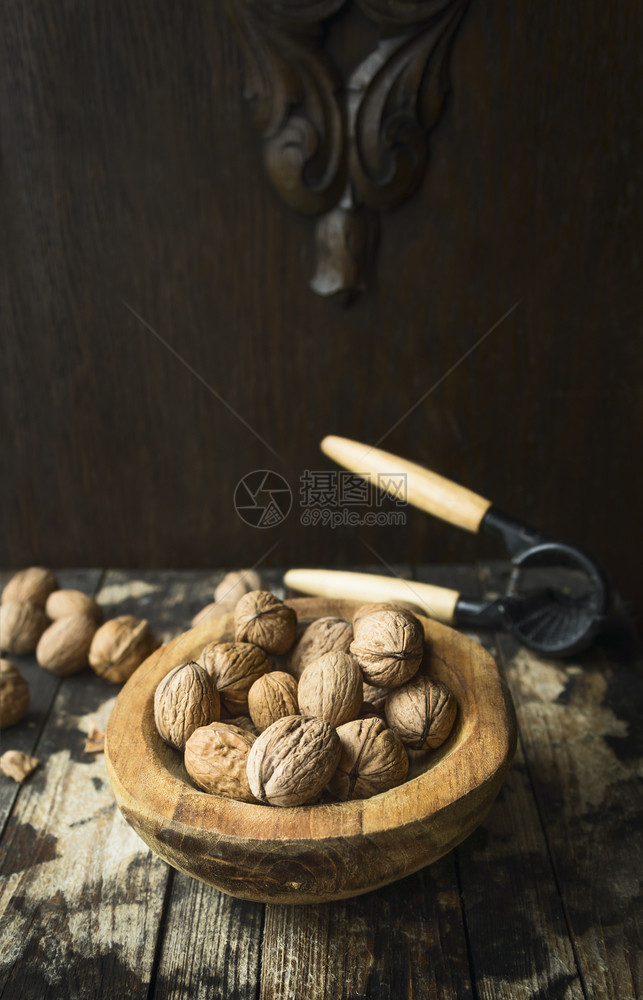 木制的碗里有和没壳的胡桃在木质生锈背景上配有因裂坚果而制成的拖具一种木头图片