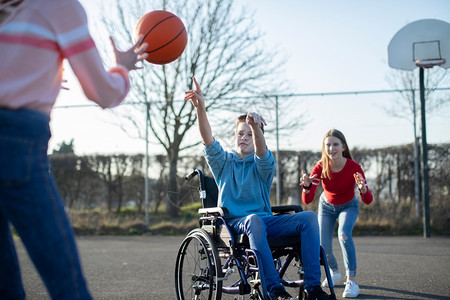 玩篮球和朋友一起打篮球的轮椅男少年孩老的身体出去图片