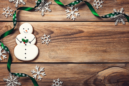 圣诞背景有姜饼干形状雪人在木制桌子上的雪人复制空间小吃丝带自制图片