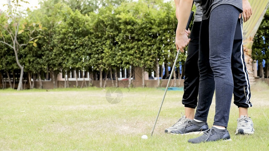高尔夫球手在花园草坪上训练高尔夫球运动员课程的男女夫妇绿色游戏图片