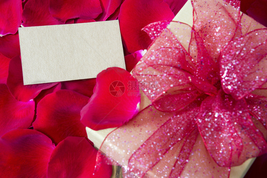自然红玫瑰花瓣背景上带礼品盒的空白标签红色婚礼图片