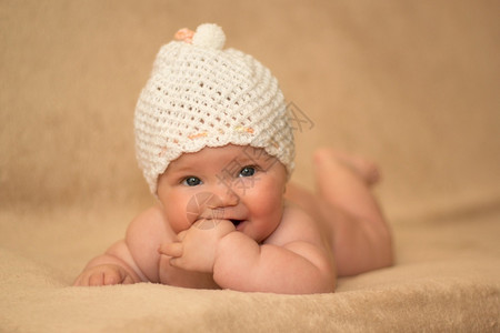 皮肤眼睛身戴白帽子躺在床上的新生女婴浅水田深处放松图片
