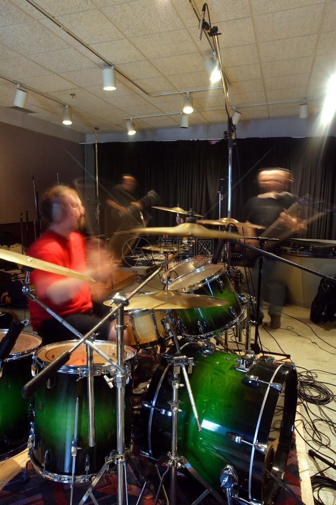 卷噪音岩石一个贝斯播放器吉他手和鼓在录音工作室的记轨中以环境灯光慢开关速度玩家运动从慢开关速度模糊起来图片
