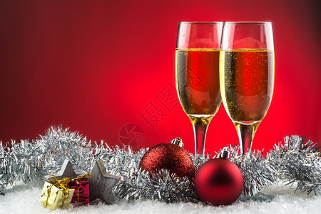 两杯雪上香槟准备用于圣诞节庆祝活动红底的酒颜色前夕礼物图片
