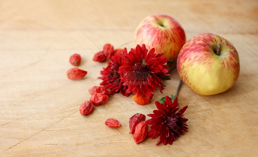 说谎小枝两块成熟的苹果躺在一串菊花和干臀边上的两片鲜红苹果上面是乳香和干屁股桌子图片