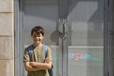 吸引人的教育快乐带着他背包好孩子站在学校门口着图片
