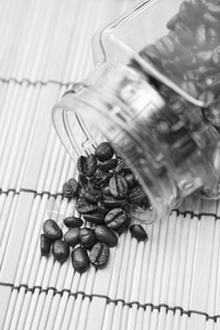 玻璃瓶中洒在桌子上的咖啡豆背景图片