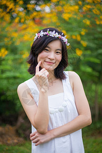 带王冠素材头发吸引人的美丽亚洲年轻女子带着一朵花的皇冠种背景