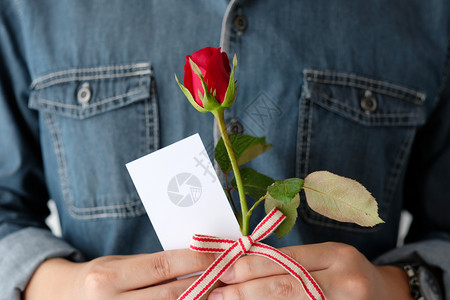 男人手拿着红玫瑰和空白纸卡图片