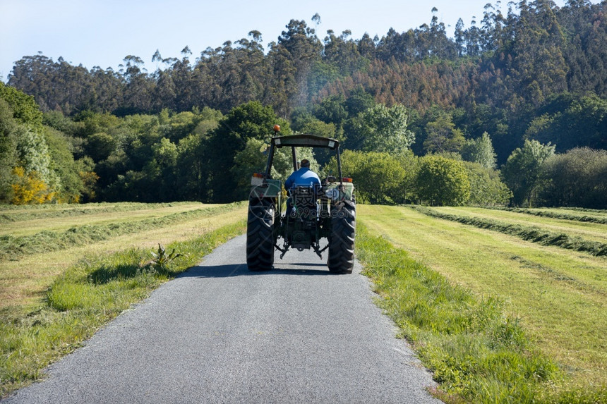 自然工业的西班牙加利亚农村地区一条公路从后面看到一辆旧拖拉机的景象在后面图片
