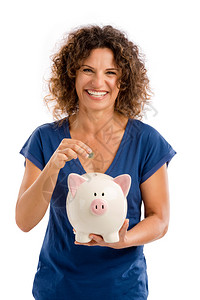 储蓄经济一个快乐的中年女人肖像把一些钱放在小猪银行上商业图片