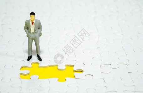 商人站在黄色背景的失踪小拼锯前在黄背上工作常设数字图片