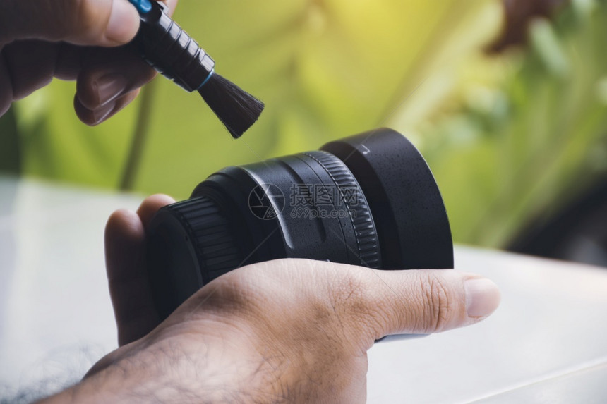 技术员摄影师镜片用笔刷清洁工照相镜头上的人类手清洗灰尘图片