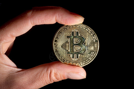 现金象征BitCoin在黑背景的拇指和食之间被持有加密货币图片