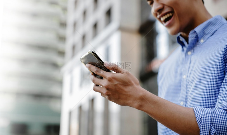 交流户外正式的利用城市裁剪图像中的移动电话和关注手力为一位笑的亚洲青年商业家关闭图片