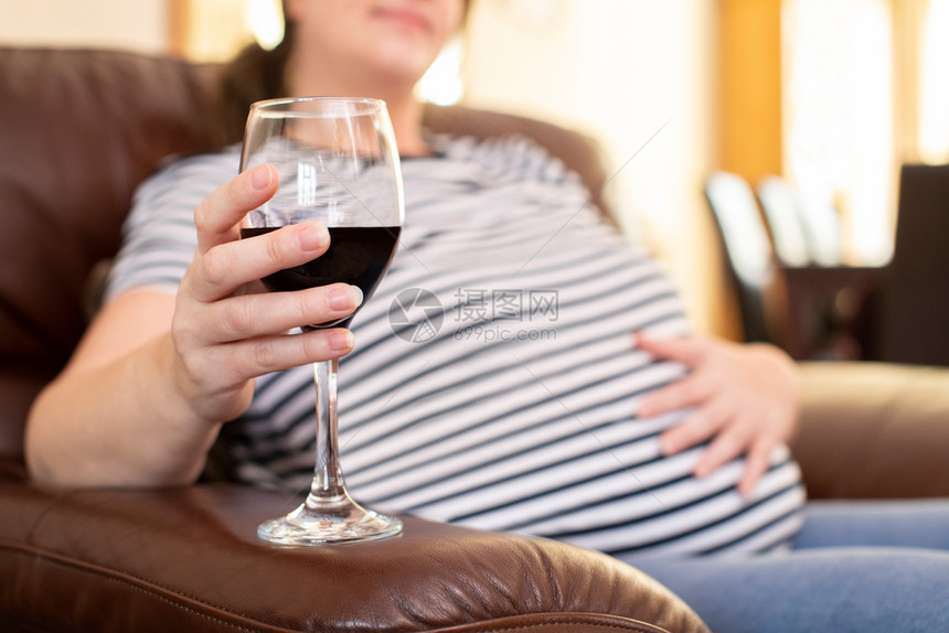 成熟人们卫生保健近距离坐在Sofa家的女孕妇饮酒红图片