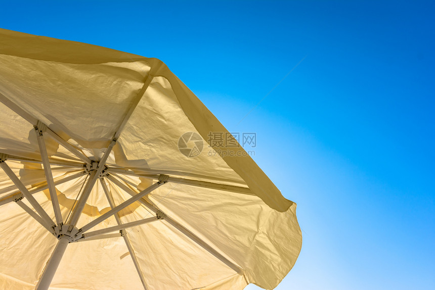 热的晴天阴凉处黄色海滩雨伞和清蓝天空图片