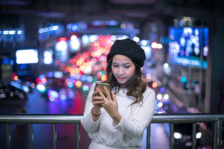 信息女士千禧一代美丽的年轻亚洲女在夜间使用手机的户外肖像画女青年图片