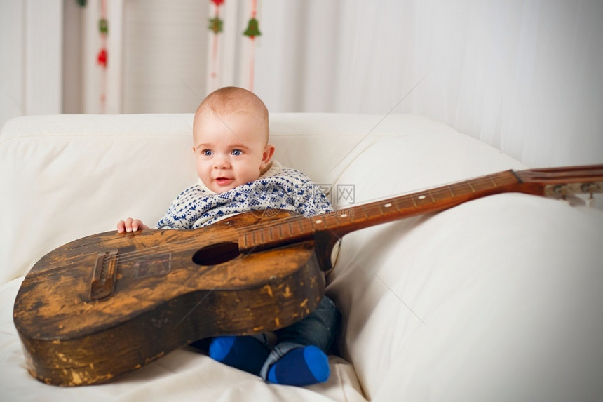 沙发上抱着吉他的婴儿图片