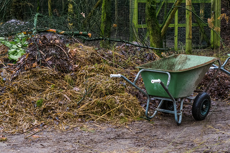 堆肥旁边的绿色手推车花园工作场所艺具农场活动桩图片