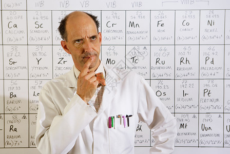 分子行业实验室中年天主教授坐在一张周期表前思考的时事图片