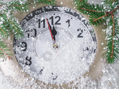 松树季节在白雪下受装饰的圣诞树下雪上有花环和圣诞装饰的时钟闪光图片