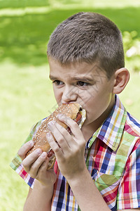 棕色的可爱男孩在吃热狗着绿色背景的食欲男人白色图片