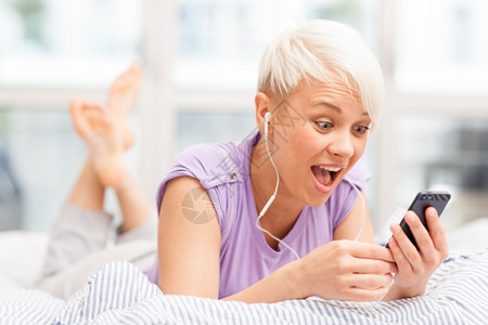 年轻女用耳机在床上打电话的照片脸交谈图片
