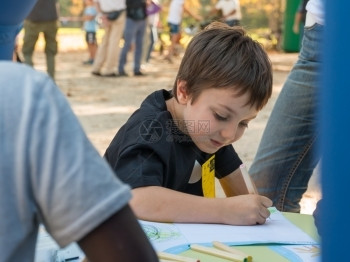 活动教育户外年轻男孩在公园里用彩色铅笔画纸图片