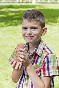 肖像黑发小可爱男孩吃热狗着有食欲的热狗黑发小可爱男孩吃着热狗理发十五背景图片