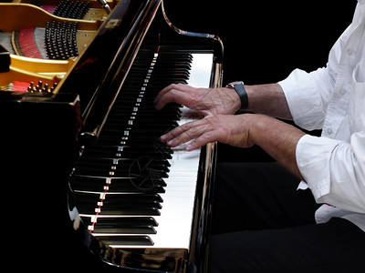 音乐家玩钢琴在一场古典爵士音乐会中亲近钢琴手的用大可口演奏黑色背景图片