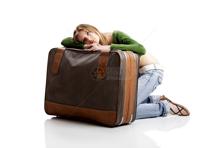 带着旧皮手提箱的美丽年轻女子等待随意的行李图片