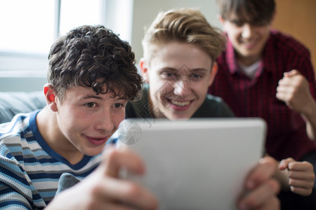 种族亚洲人在家数字板上玩游戏的3名少年男孩享受图片