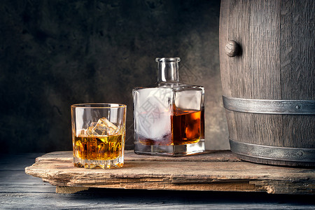 降低一杯带冰酒瓶和木桶的威士忌酒杯一带冰瓶和桶的威士忌桌子苏格兰人图片