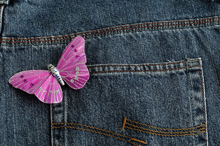 粉红色蝴蝶由丝绸制成展示在牛仔的后袋口粉色美丽单身背景图片