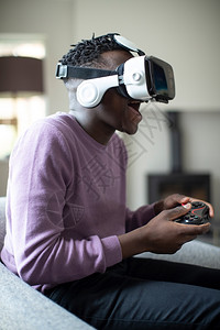 眼镜兴奋的青少年男孩在家中穿着虚拟现实耳机玩视频游戏快乐的男人图片