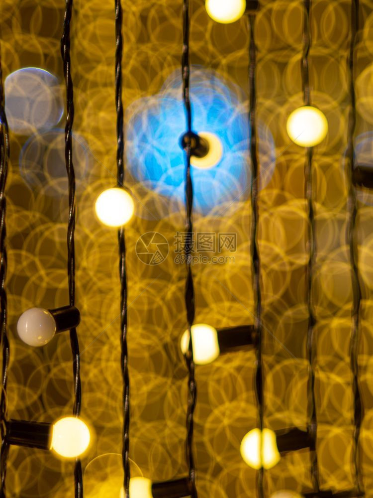 明亮的黄色bokeh夜间用电灯在挂有铁线的泡后面脱光在喜庆的图片