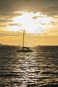 太阳海上阳光下航行的帆船反射海面云图片