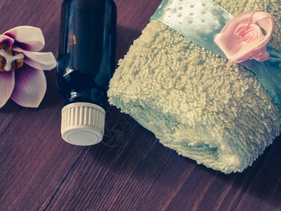 海洋烛光毛巾水浴用油瓶和木底按摩用头背景的按摩毛巾和一瓶油碗图片