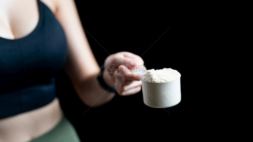 酪蛋白舀活力女手持乳清蛋白量勺制备奶昔的特写图片