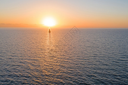 日落时从海上航行的帆船图片
