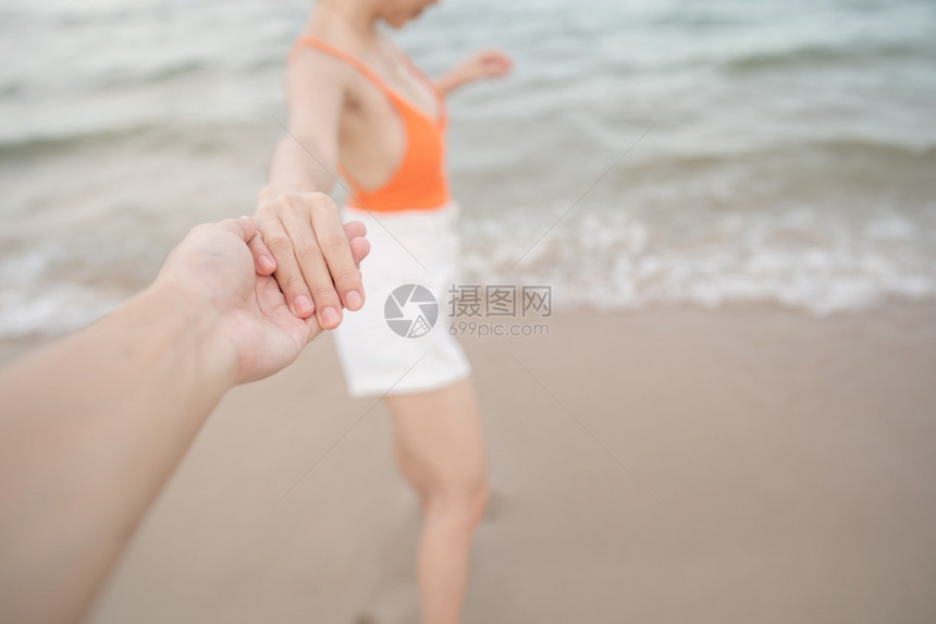 户外女人牵着男朋友的手在海滩上一起跑来去人们自然图片