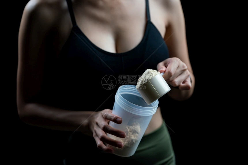 运动替换肌肉近距离接女测量一勺威氏蛋白质和摇晃瓶制作蛋白奶昔图片