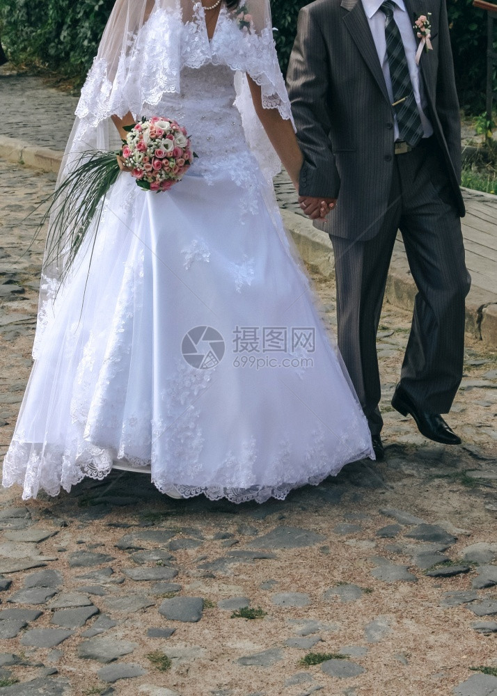 新婚夫妇在城市街道的cobblestone上行走幸福已婚缎图片